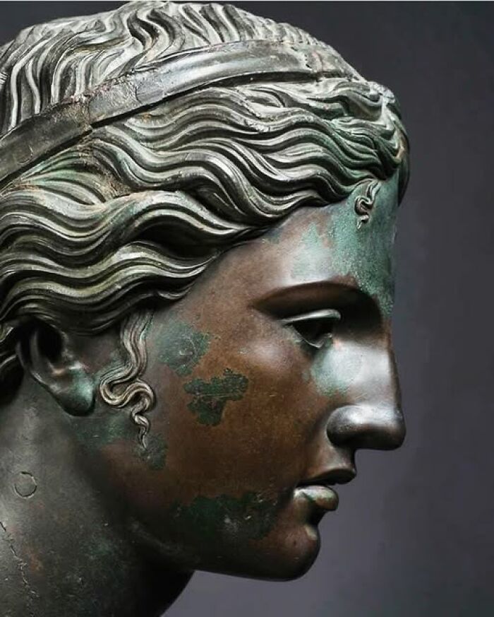 Bronze sculpture of a classical figure showcasing detailed hair and facial features, an archeological art wonder.