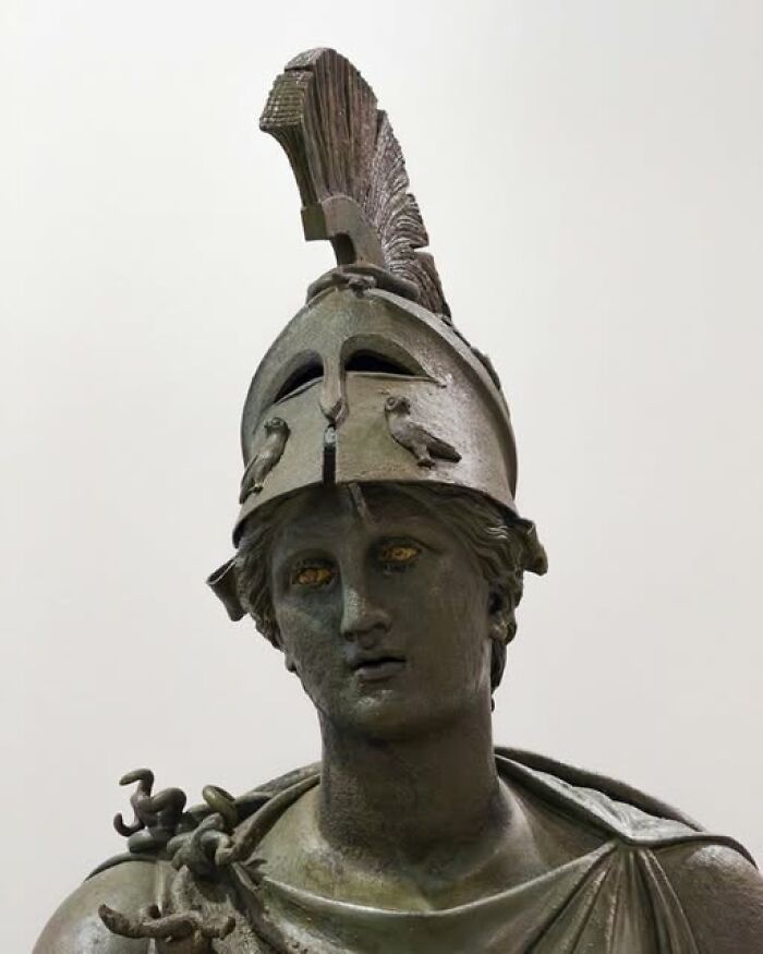 Bronze statue of a warrior wearing a decorated helmet, representing archeological art and ancient craftsmanship.