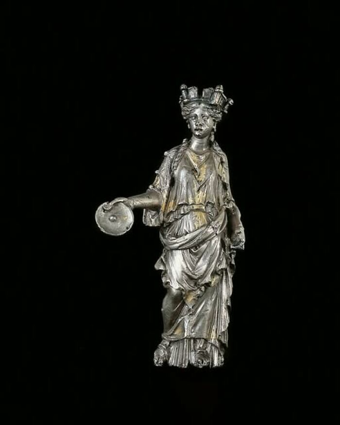 Silver figurine of a robed woman holding a disc, an archeological wonder blending archeology and art from ancient times.