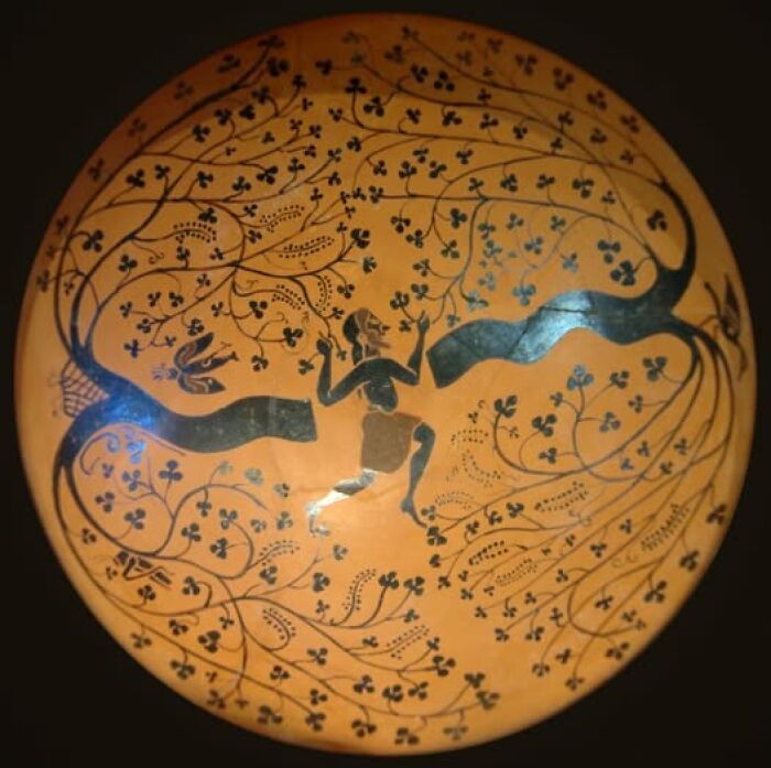 Ancient archeology and art pottery featuring a human figure surrounded by intricate floral and vine patterns.