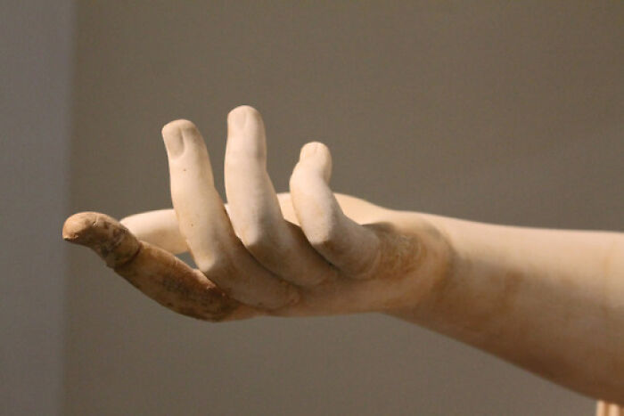 Close-up of an ancient marble hand sculpture showcasing detailed archeology and art craftsmanship from a historic period.