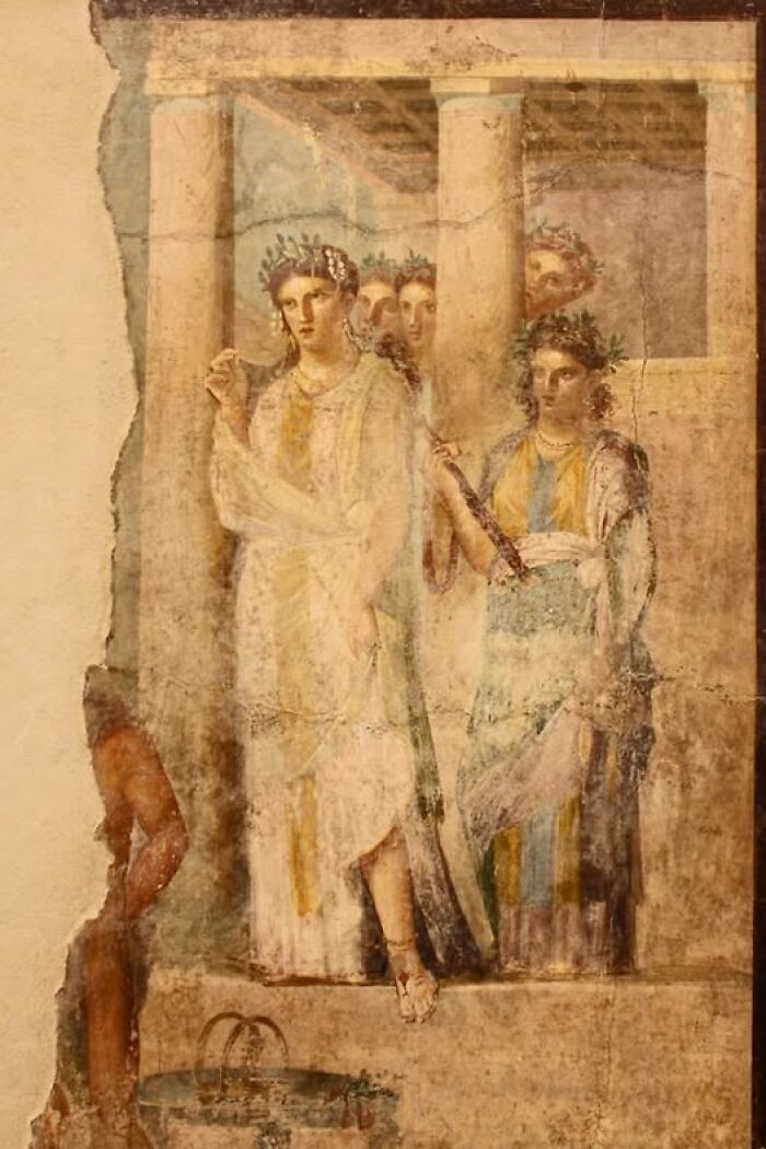 Ancient fresco depicting women in robes and laurel wreaths, showcasing archeology and art in historical context.
