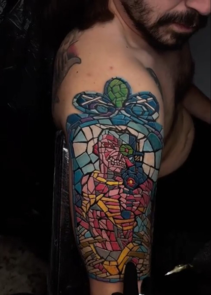 Man with colorful mosaic style tattoo covering upper arm, highlighting the tattoo boom cooling off in 2025.
