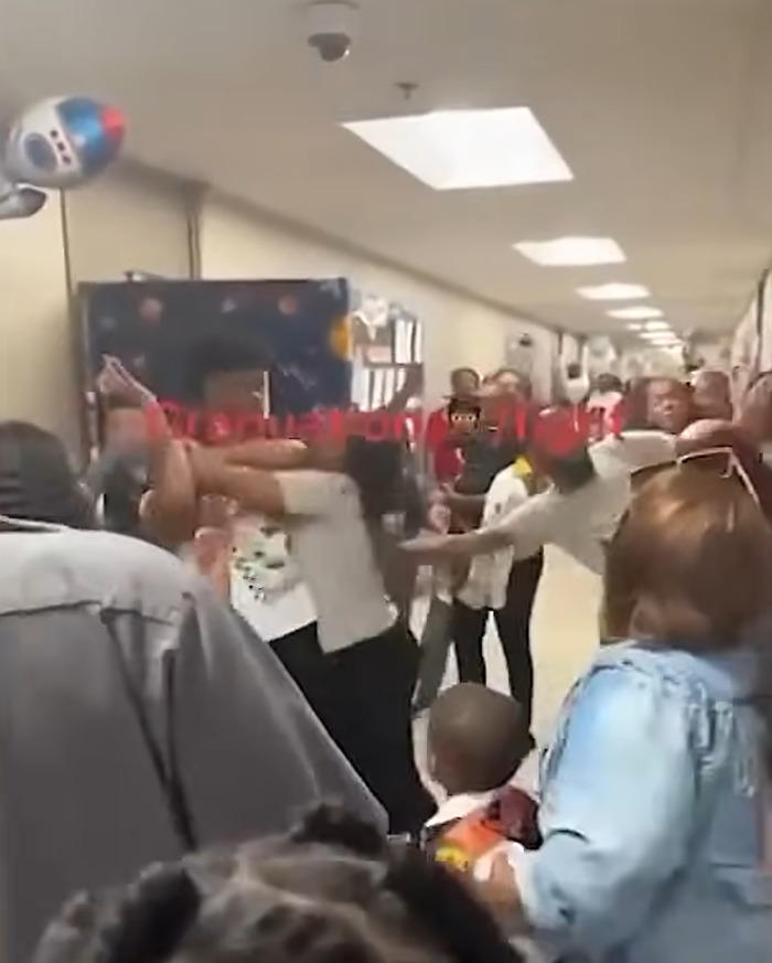 Parents in a traumatic brawl at a kindergarten graduation hallway while children watch and plead for peace.