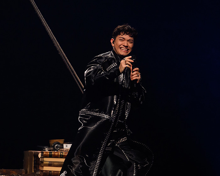 Austrian performer smiling on stage wearing a black studded outfit during Eurovision 2025 victory performance.