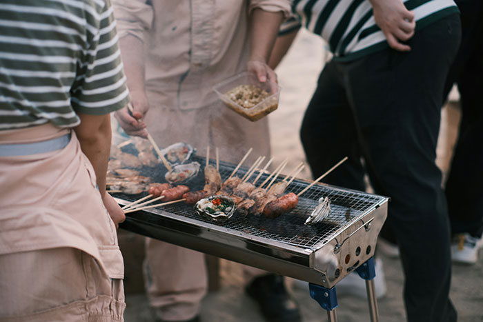 People grilling skewers and seafood on a barbecue, capturing massive awkward moments ignored by everyone in the room