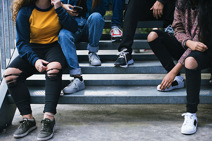 Group of young people sitting on outdoor stairs, dressed casually, illustrating the concept of the biggest elephant in the room.