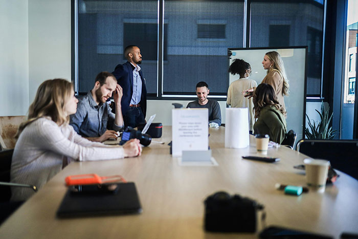 A group of coworkers in a meeting room appearing thoughtful and silent, facing the biggest elephant in the room.