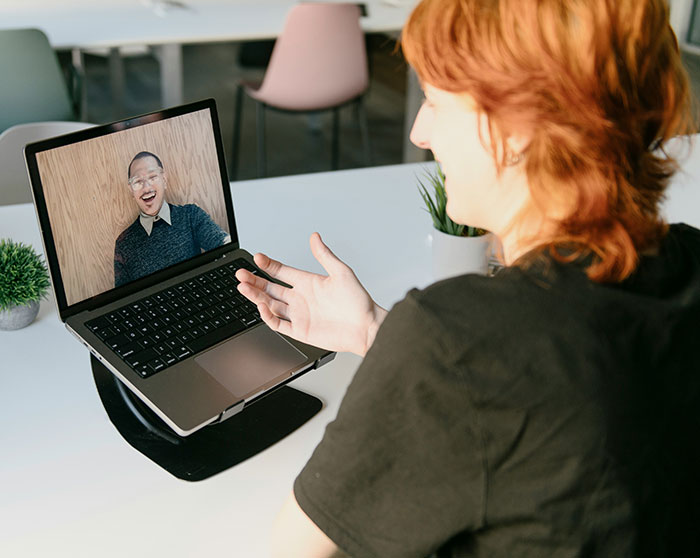 Person with red hair video chatting on laptop, illustrating the concept of the biggest elephant or blue whale in the room.