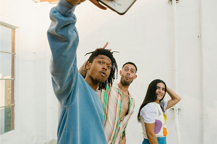 Three friends taking a selfie indoors, representing HR employees sharing stories about background checks they've seen.