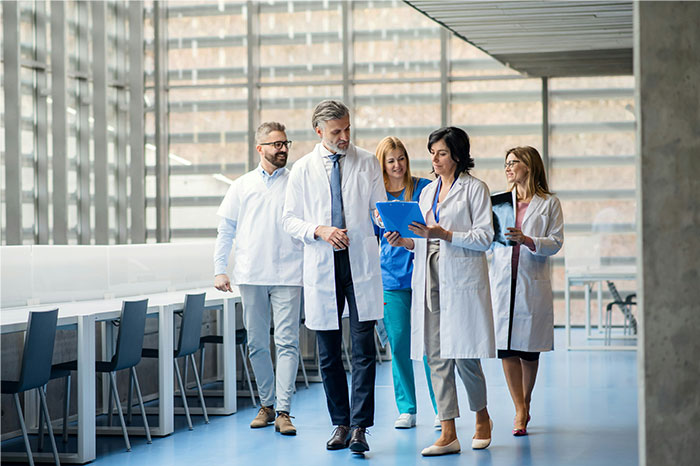 Group of HR employees in lab coats discussing and reviewing documents during a background check process in a modern office.
