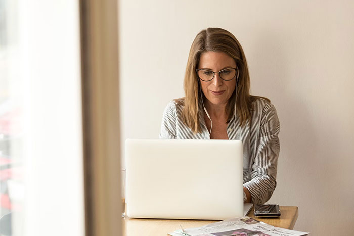 HR employee with glasses working on laptop in a minimal office setting, illustrating background checks process.