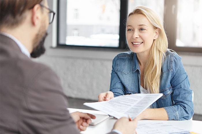 HR employees conducting background checks during a job interview, reviewing documents in a modern office setting.