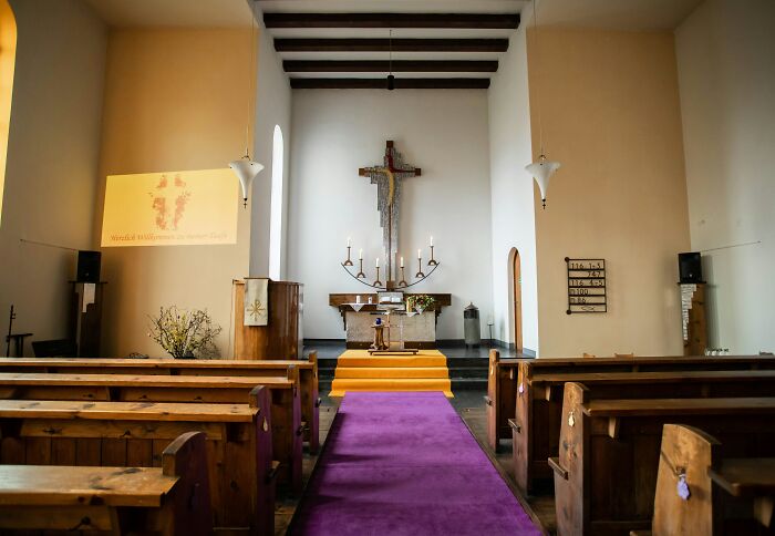 Interior of a church with wooden pews and a cross, illustrating mind-boggling beliefs some smart people still stand behind.