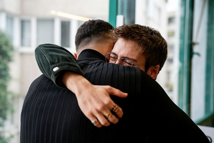Two men embracing with emotional expressions, capturing shocking and unreal experiences people have lived through.