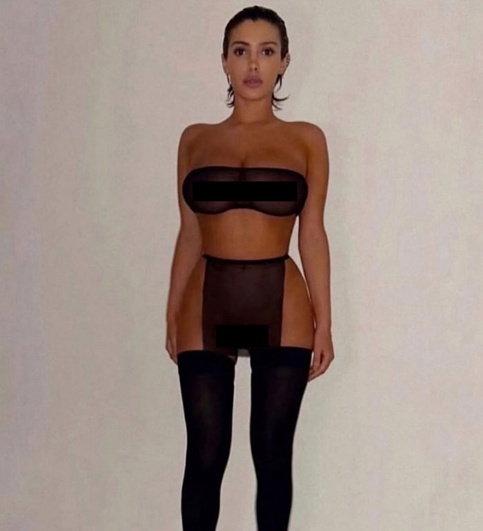 Bianca Censori posing confidently in sheer black lingerie with thigh-high stockings against a plain background.