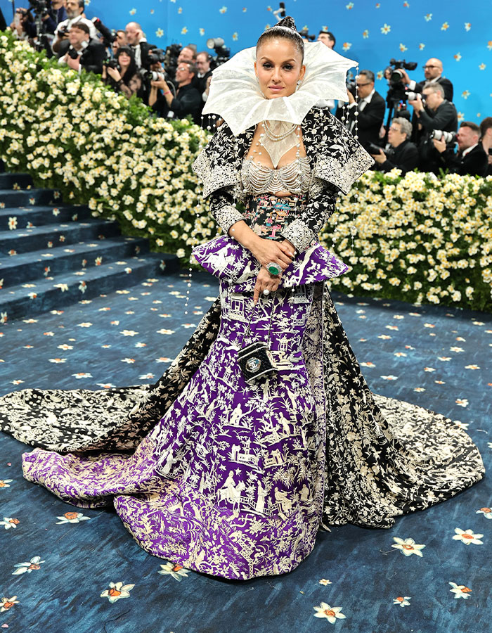 Woman in elaborate black and purple patterned gown with oversized white collar at Met Gala fashion fails 2025 event.