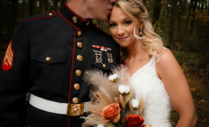 Groom in military dress uniform kisses bride holding bouquet, symbolizing serving country and family support. Groom in military dress uniform kisses bride holding bouquet, symbolizing serving country and family support.