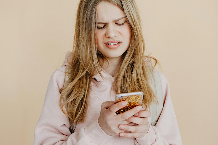 Young woman looking confused at her phone, expressing concern related to a man signing up to serve his country. Young woman looking confused at her phone, expressing concern related to a man signing up to serve his country.