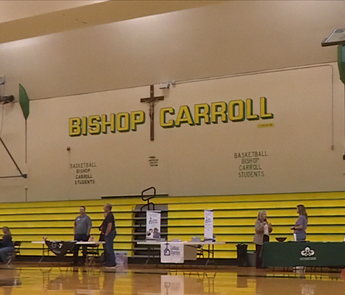 Bishop Carroll gymnasium with people setting up tables, relating to high school valedictorian controversy over speech.