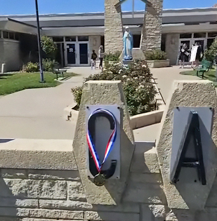 High school valedictorian medal hanging on school sign, symbolizing punishment must fit the crime controversy over speech.