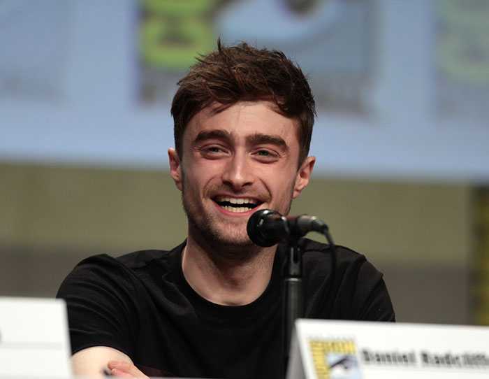 Actor smiling at a panel microphone during an event about strange ways people cross paths with celebs.