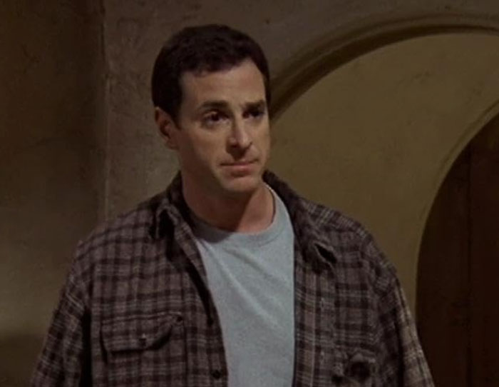 Man in plaid shirt indoors, looking thoughtful, illustrating strange ways people cross paths with celebs.