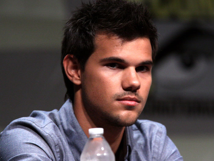 Young man speaking at event, capturing the essence of strange ways people have crossed paths with celebs.