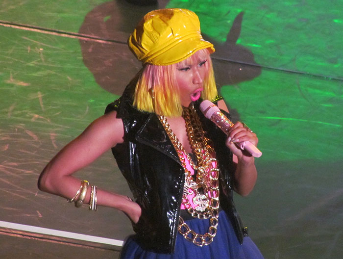 Female celebrity performing on stage wearing a yellow hat and colorful outfit, illustrating strange ways people crossed paths with celebs