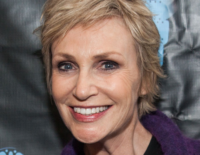 Close-up of a smiling woman with short blonde hair, illustrating people sharing strange ways they've crossed paths with celebs.