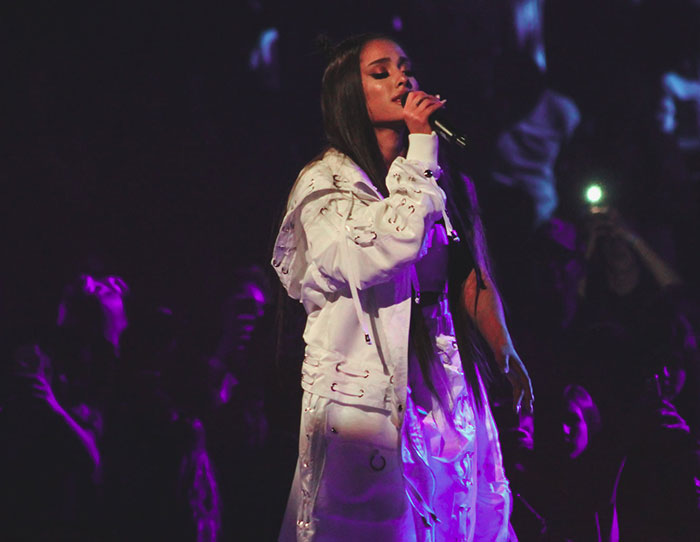 Female singer performing on stage with microphone, capturing the strangest ways people have crossed paths with celebs.