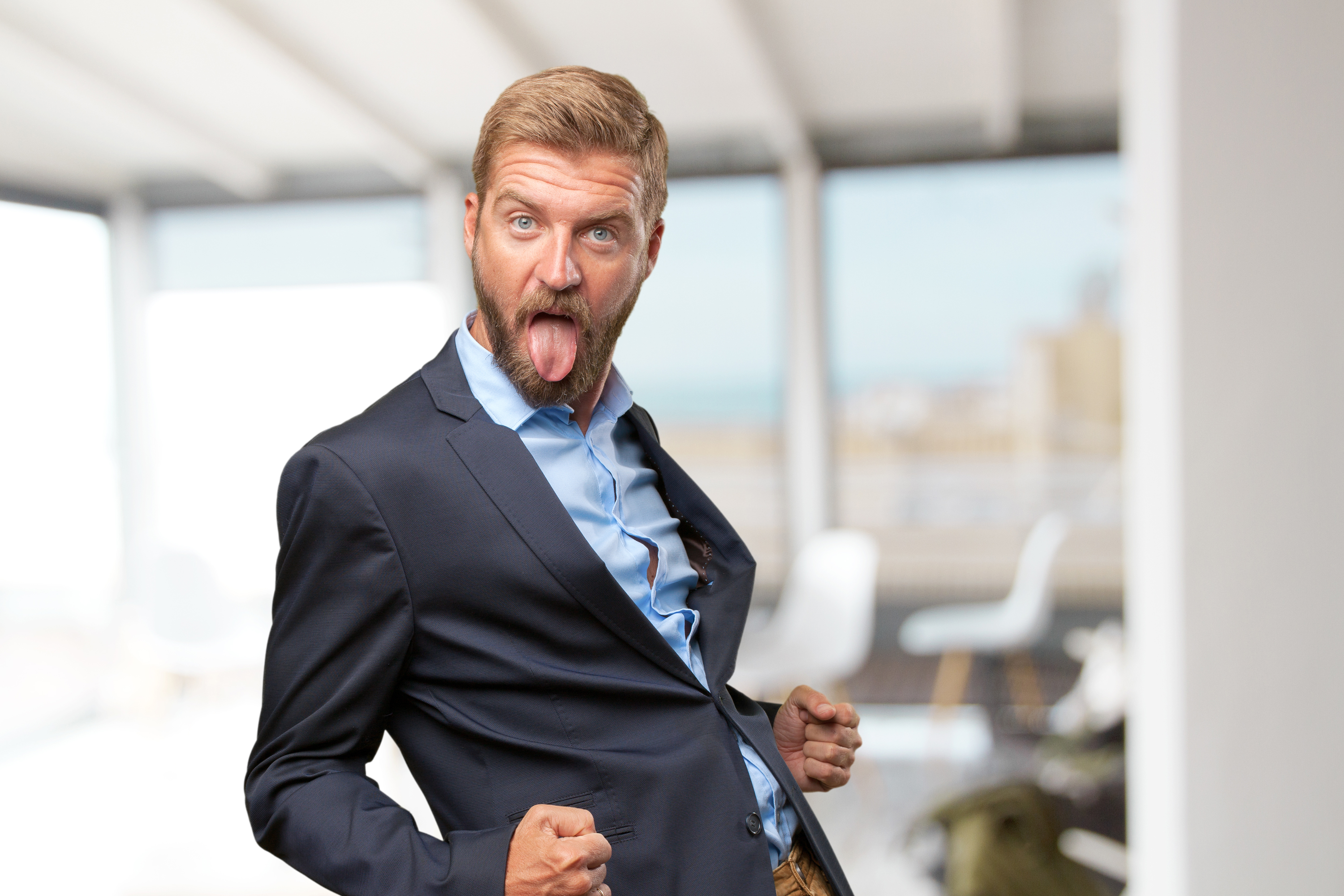 Man in suit making a funny face with tongue out, showing petty and satisfying revenge emotions in office setting. Man in suit making a funny face with tongue out, showing petty and satisfying revenge emotions in office setting.