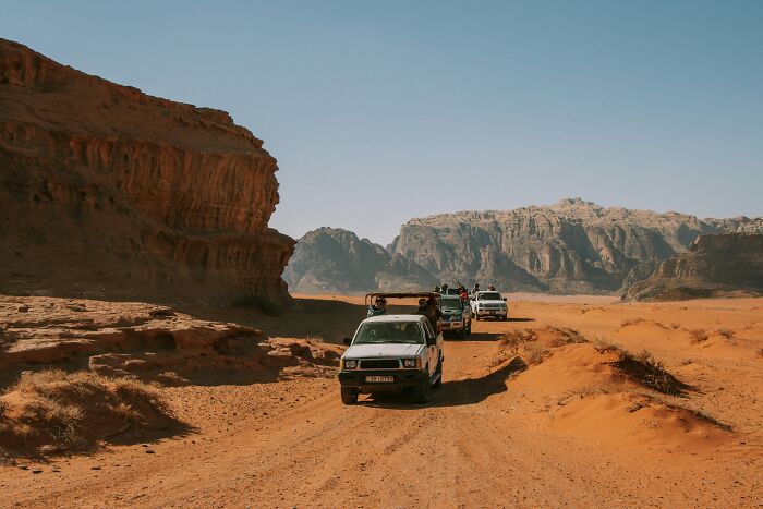 Four off-road vehicles driving through a desert landscape showcasing must-see wonders of the world full of magic.