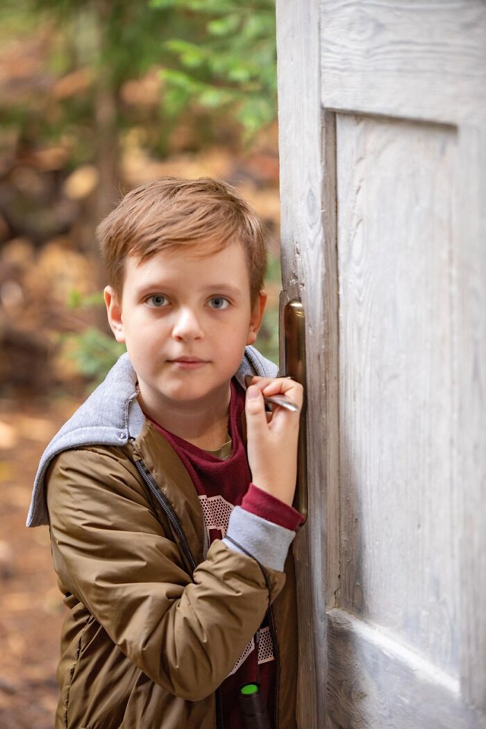Young boy standing by a wooden door outdoors, illustrating hilariously bad names that make people question parenting choices.