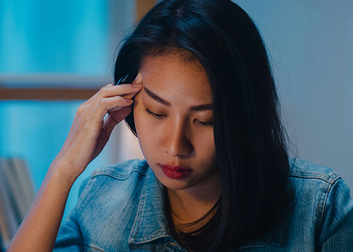Woman looking thoughtful and concerned indoors, reflecting on a guy who always brings BFF to dates.