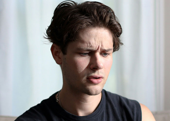 Young man with furrowed brow looking confused, reflecting emotions tied to guy always bringing BFF to dates story.