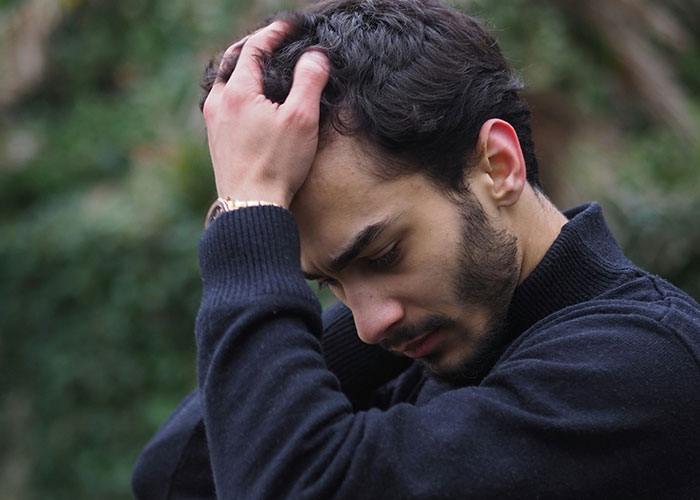 Young man looking stressed outdoors, symbolizing the guy always brings BFF to dates unhinged truth.