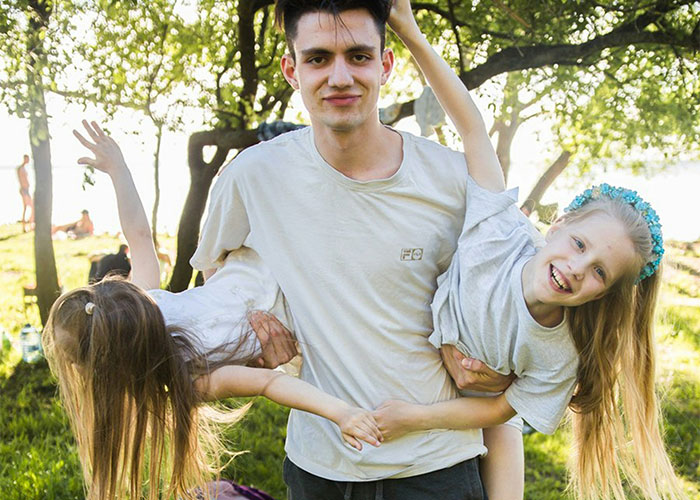 Man holding two happy girls outdoors, looking tired after watching 4 kids on a trip with girlfriend’s family. Man holding two happy girls outdoors, looking tired after watching 4 kids on a trip with girlfriend’s family.