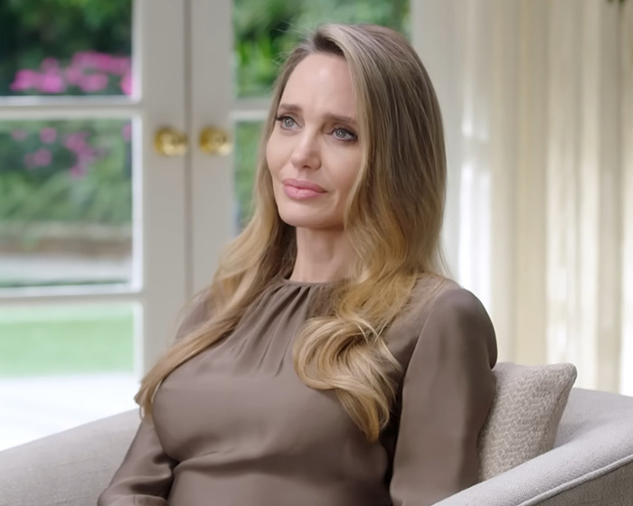 Angelina Jolie sitting indoors with soft lighting, reflecting on Brad Pitt divorce battle ending after eight years.