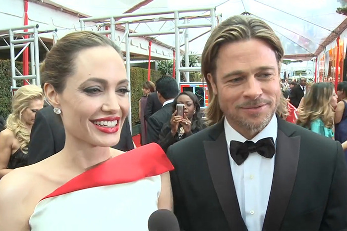 Brad Pitt and Angelina Jolie smiling on red carpet at an event amid divorce battle updates and media attention.