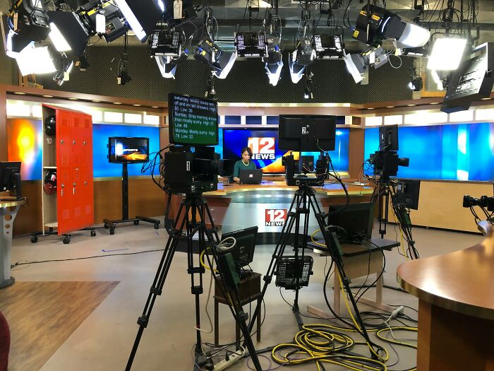 News studio with cameras, lighting, and a presenter working on a laptop, illustrating jobs earning more than expected.