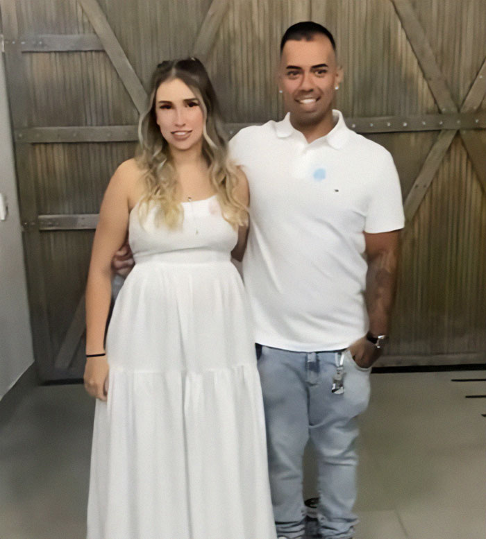 Couple in white clothing posing indoors during a baby's gender reveal event sparking a heated debate.