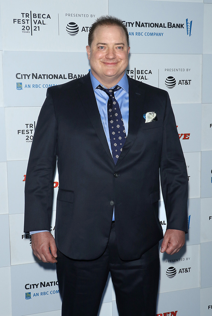 Brendan Fraser in a dark suit and patterned tie, smiling while attending a cancer gala event.