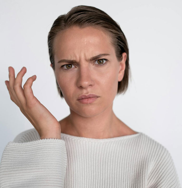 Confused woman with furrowed brows expressing frustration about couple ganging up on maid of honor for wedding planning. Confused woman with furrowed brows expressing frustration about couple ganging up on maid of honor for wedding planning.