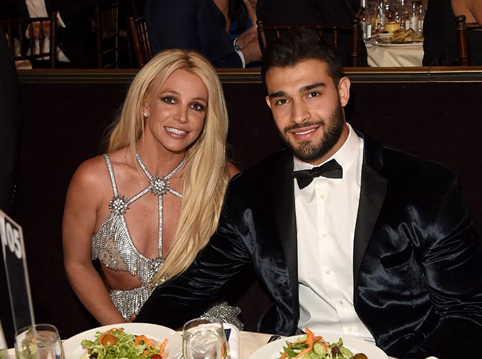Britney Spears and Sam Asghari seated at a dinner table, dressed elegantly at a formal event.