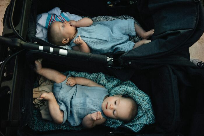 Two babies dressed in blue outfits lying in a suitcase, illustrating hilariously bad baby names that confuse people.