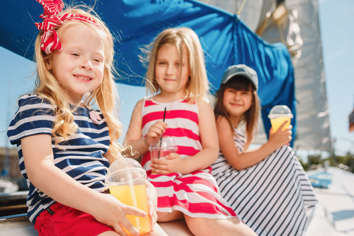 Three children enjoying drinks on a boat during vacation highlighting parents using couple for free babysitting. Three children enjoying drinks on a boat during vacation highlighting parents using couple for free babysitting.