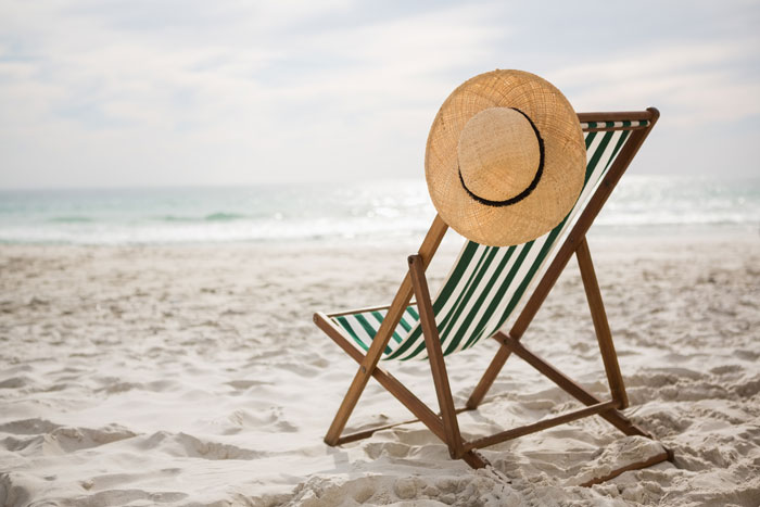 Beach chair with a straw hat on white sand, symbolizing vacation and parents using couple for free babysitting. Beach chair with a straw hat on white sand, symbolizing vacation and parents using couple for free babysitting.