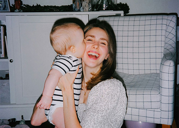 Young woman smiling happily while holding a baby, illustrating feelings related to treating kids differently in family dynamics.