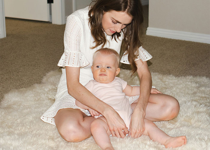 Young woman sitting on a rug with a baby, illustrating a family dynamic and treatment differences between kids.